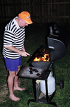 Jim grilling some spicy sausages on the grill late at night.