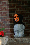 Cement pig wearing a Halloween mask.
