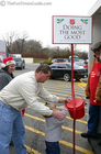 Karly stuffing a dollar in the Salvation Army bell ringer's bucket.
