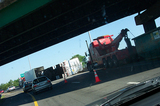 A tow truck about to haul off a tipsy beer truck. The beer truck dumped its load during morning rush hour traffic, spilling beer all over I-65!
