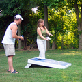 Wes and Abby laughing while playing a game of Cornhole.