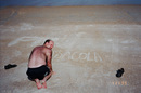 Jim drawing 'Pensacola or Bust' in the sand on the beach