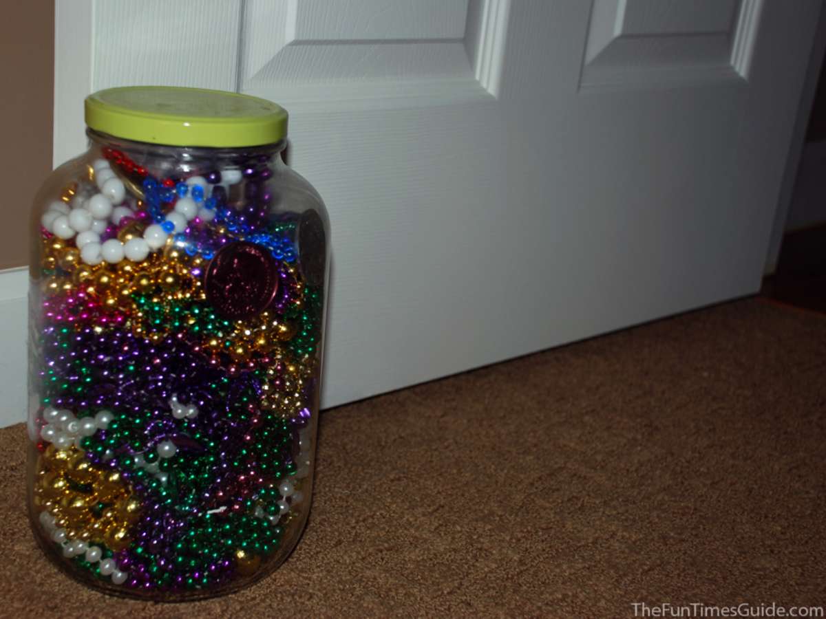 A large pickle jar filled with Mardi Gras beads and used as a door stop. 