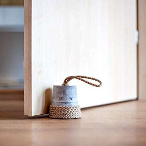 A simple but rustic DIY door stop is to use an empty tin can or bucket filled with something heavy and decorated with fabric rope -- like jute or hemp.